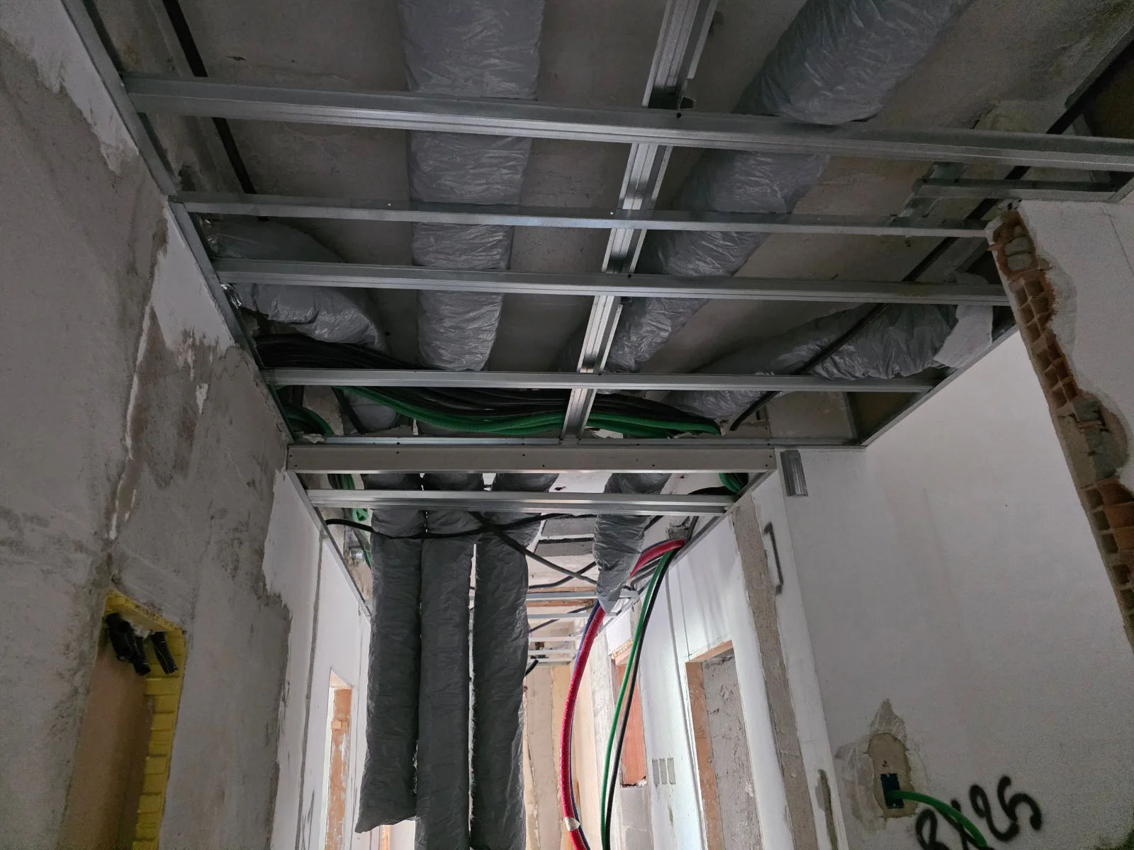 Canalizzazioni isolate per la climatizzazione e la ventilazione posate in controsoffitto lungo un corridoio, cantiere ECO-E